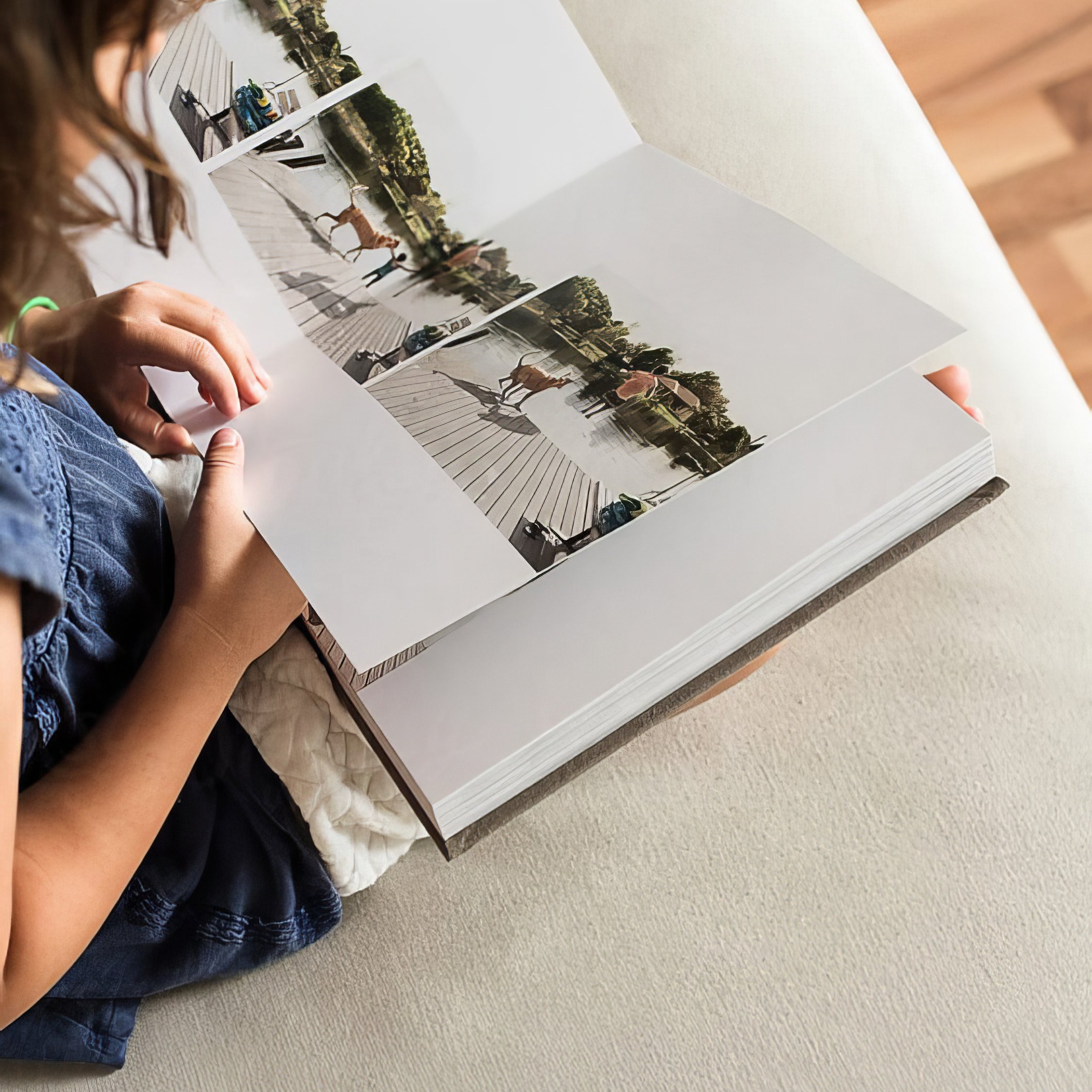 Person leafing through a printed photo album on the floor.