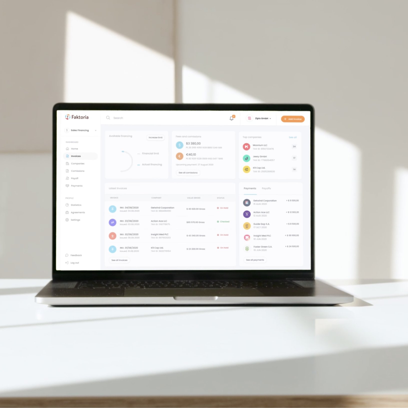 Laptop on a white desk displaying the Faktoria invoice list.