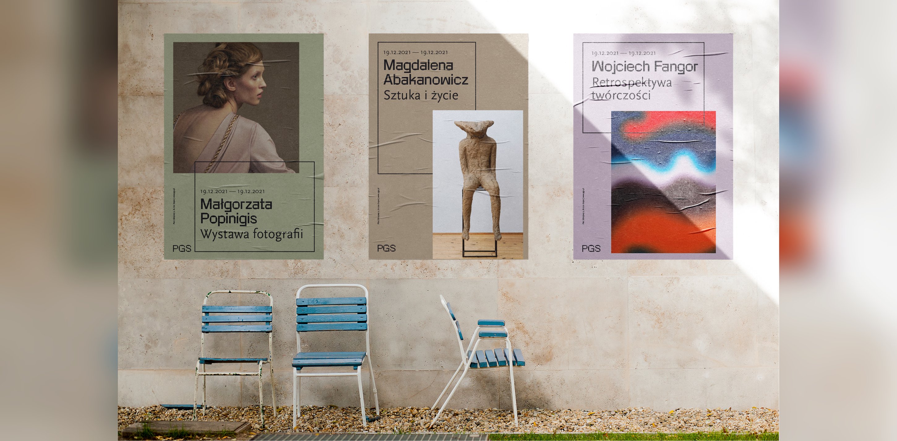 Exhibition posters pasted on a wall above a row of chairs.