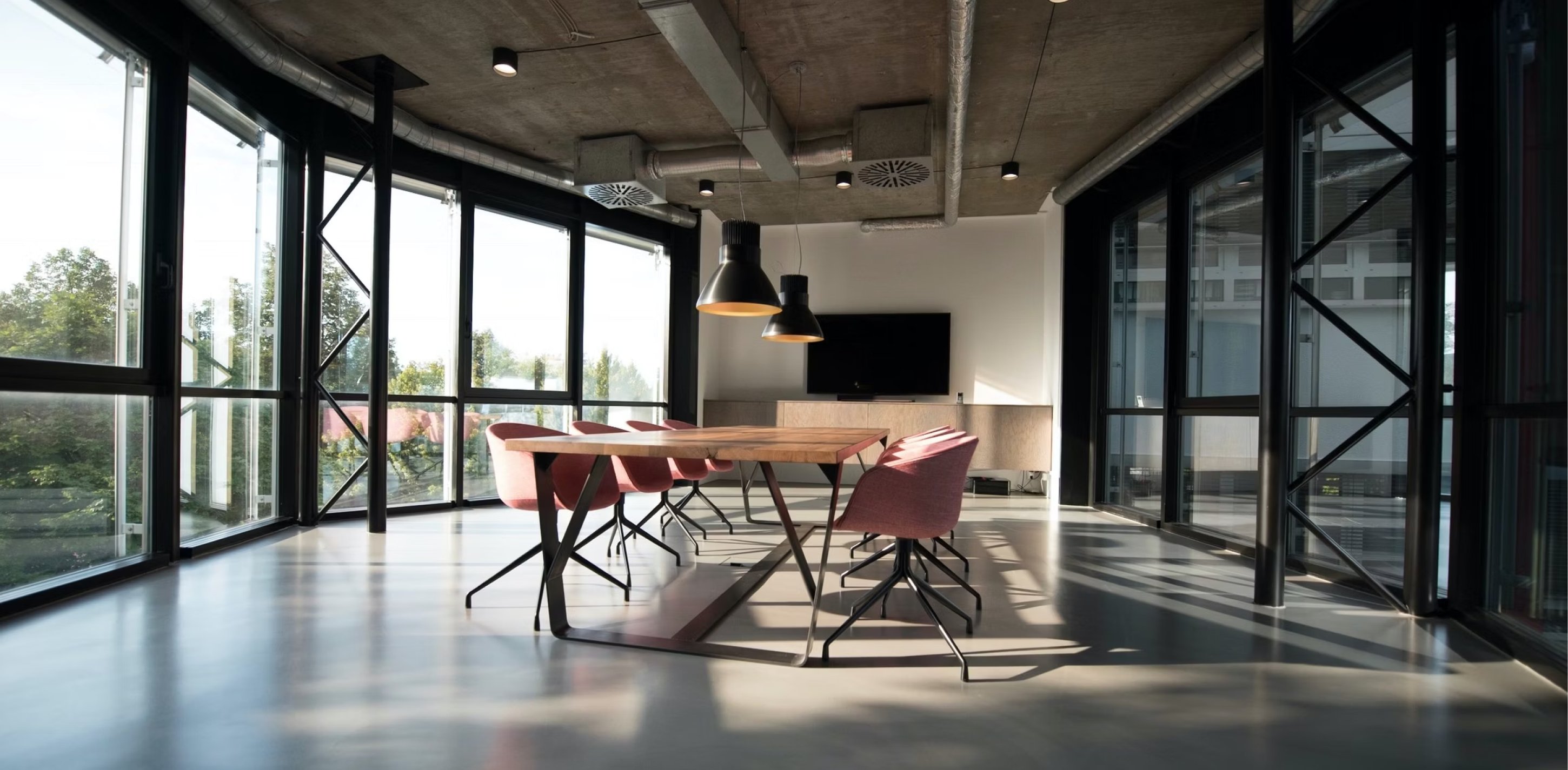 WeWork meeting space with a long wooden table and floor-to-ceiling windows.